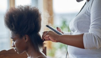 A young woman having her hair straightened. In preparation for hair braids