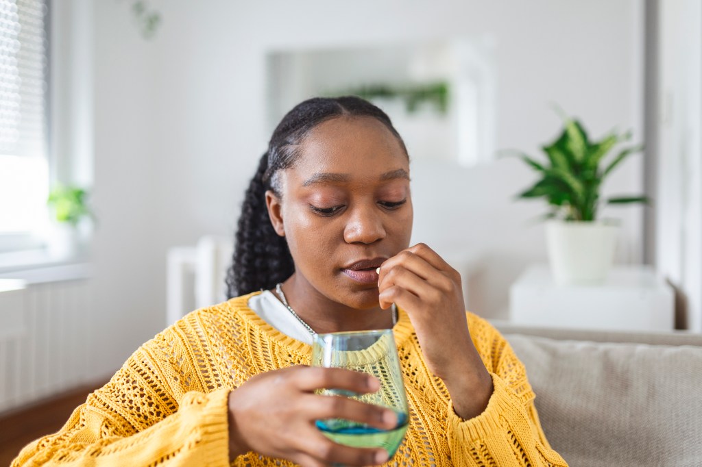 A Black woman taking a supplement