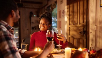 Happy black woman having a meal with her husband in dining room.